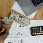 Mãos digitando em um teclado com uma planilha Excel aberta na tela do computador, exibindo gráficos financeiros.