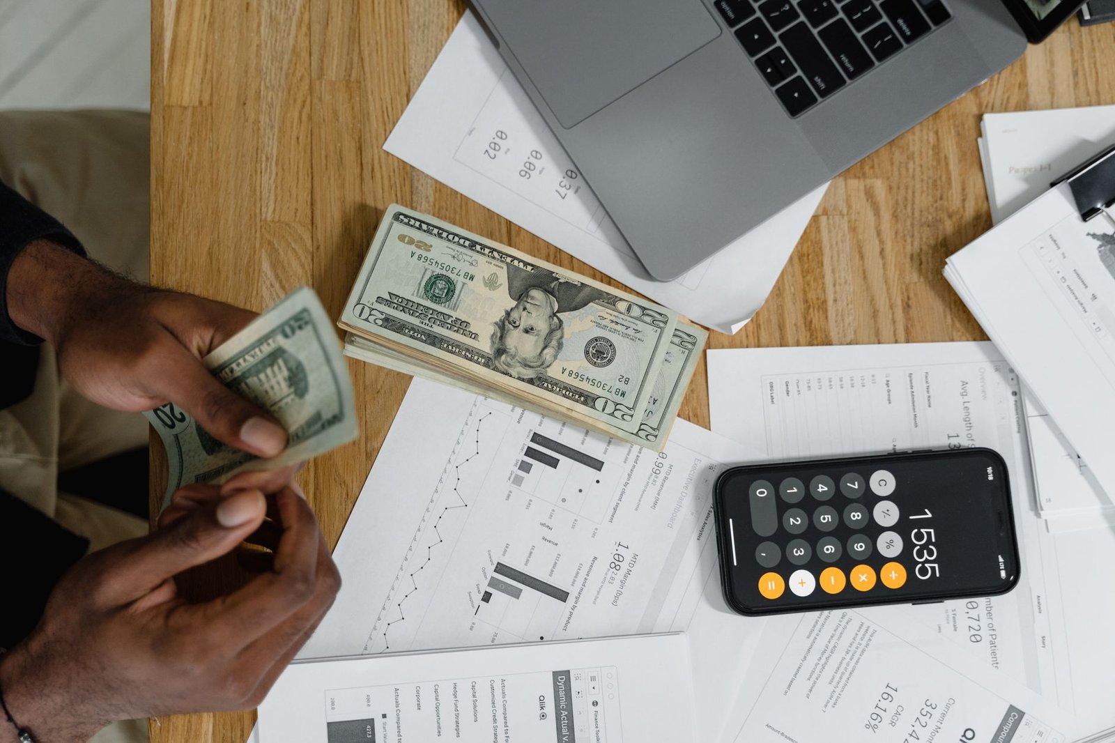 Mãos digitando em um teclado com uma planilha Excel aberta na tela do computador, exibindo gráficos financeiros.