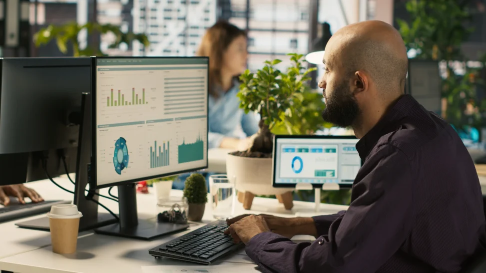 Pessoas trabalhando em laptops com gráficos de vendas e ícones de CRM, representando a gestão de clientes em PMEs.