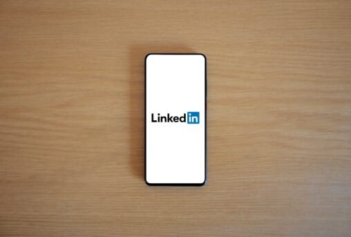 Duas pessoas, uma falando ao telefone (Cold Calling), outra usando um laptop com o LinkedIn (Social Selling), simbolizando a comparação de estratégias de vendas.